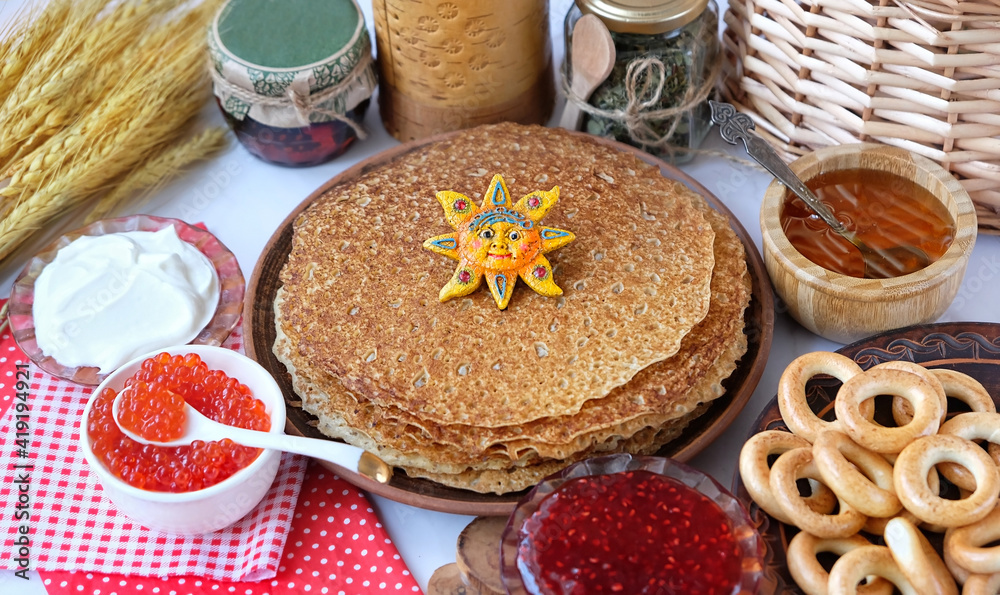 Pancakes with sun symbol, red caviar, jam, honey, bread bagels on table. Maslenitsa holiday, pancakes week. traditional slavic festival meal. Pancakes with sun symbol, red caviar, jam, honey, bread bagels on table. Maslenitsa holiday, pancakes week. traditional slavic festival meal.