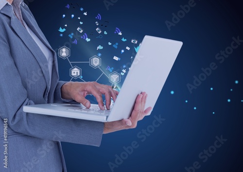 Network of digital icons over mid section of businesswoman using laptop against blue background photo