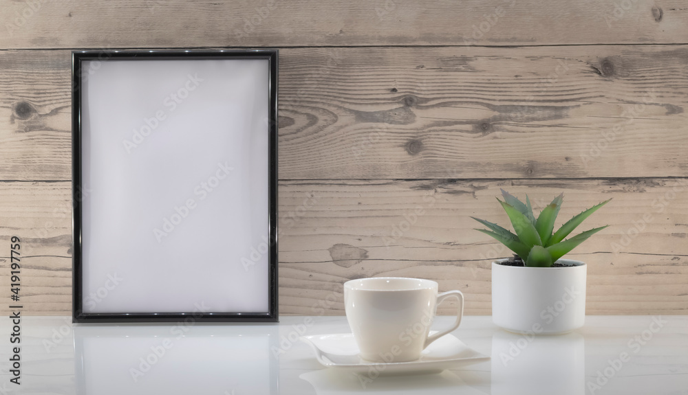 Modèle de cadre photo blanc avec espace vide pour logos, inscription publicitaire. Cadre en mode portrait sur un espace de travail avec une tasse. Ambiance zen.