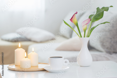 cup of coffee and flowers in vase on white table indoor