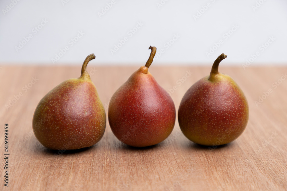 Three homegrown organic pears on a wooden surface with a white backdrop Three homegrown organic pears on a wooden surface with a white backdrop