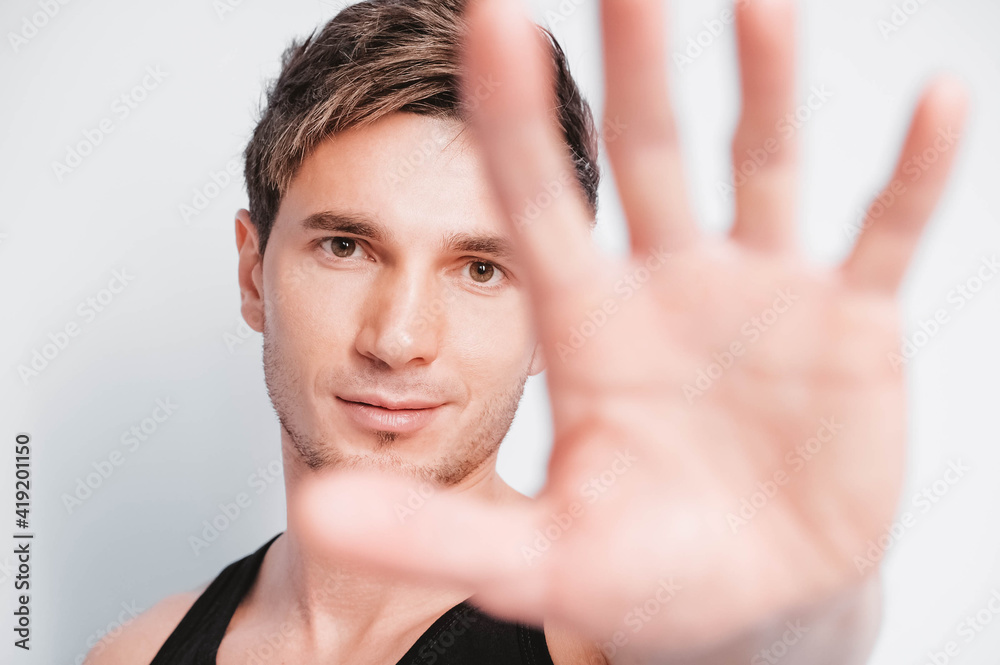 Portrait of a young man covering his face with his hand on a white background. Copy, empty space for text Portrait of a young man covering his face with his hand on a white background. Copy, empty space for text
