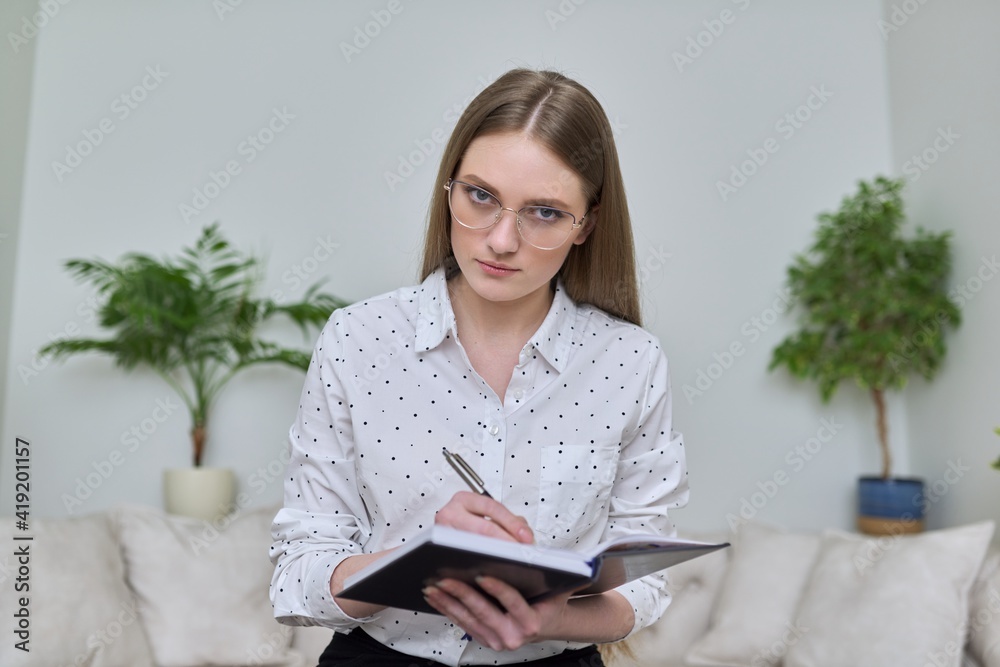Young businesswoman with business notebook looking at webcam Young businesswoman with business notebook looking at webcam