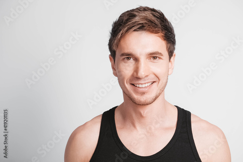 Portrait of a young smiling man wearing a black T-shirt on a white background. Copy, empty space for text