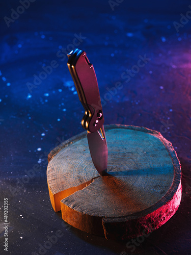 Stylish stainless steel folding knife, crack in wood. Quality steel, color neon style photo photo