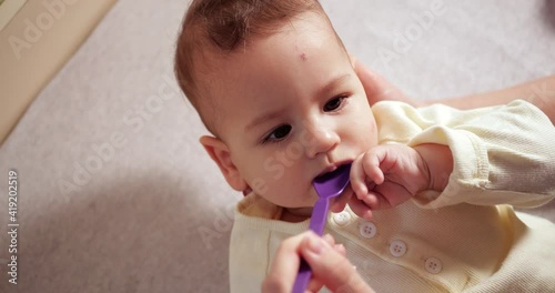 Hands of mom giving cough syrup medicine on spoon to sick little son. health and medicine baby concept. slow motion