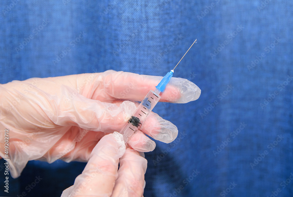 In her hands in transparent medical gloves syringe with medicine, on the needle drops . In her hands in transparent medical gloves syringe with medicine, on the needle drops .