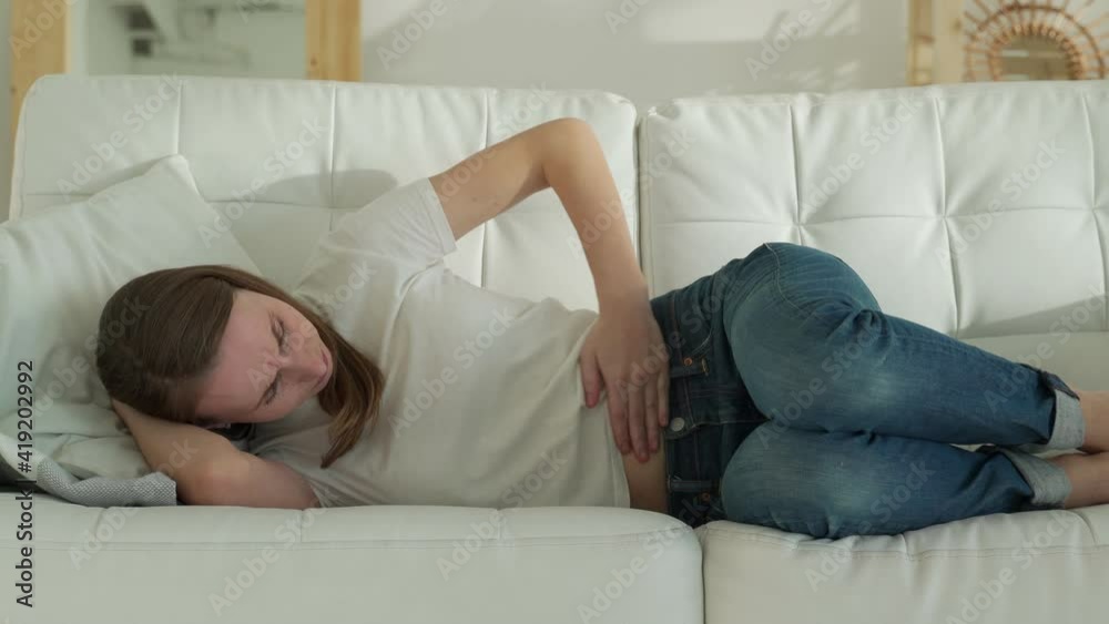 Women have abdominal pain because of menstruation. She was lying in sofa and holding her stomach. Women have abdominal pain because of menstruation. She was lying in sofa and holding her stomach.