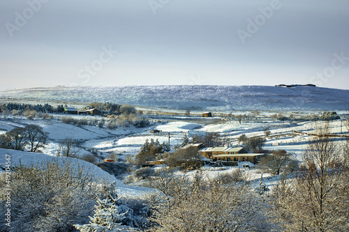 Fototapeta Naklejka Na Ścianę i Meble -  Farmland and homes and a snowy view in the Yorkshire Dales at 900ft
