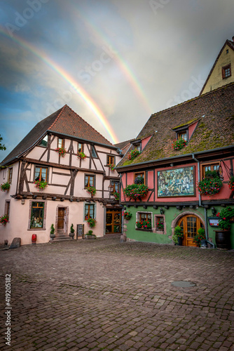 podwójna tęcza nad kolorowymi domkami w średniowiecznej wiosce Riquewihr, Alzacja, Francja