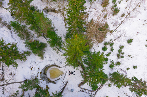 A woman admires the winter landscape in the forest. Photo from the drone. Glacial potholes in Askol, Finland. photo