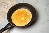 Pancake is fried in a pan on an induction hob.