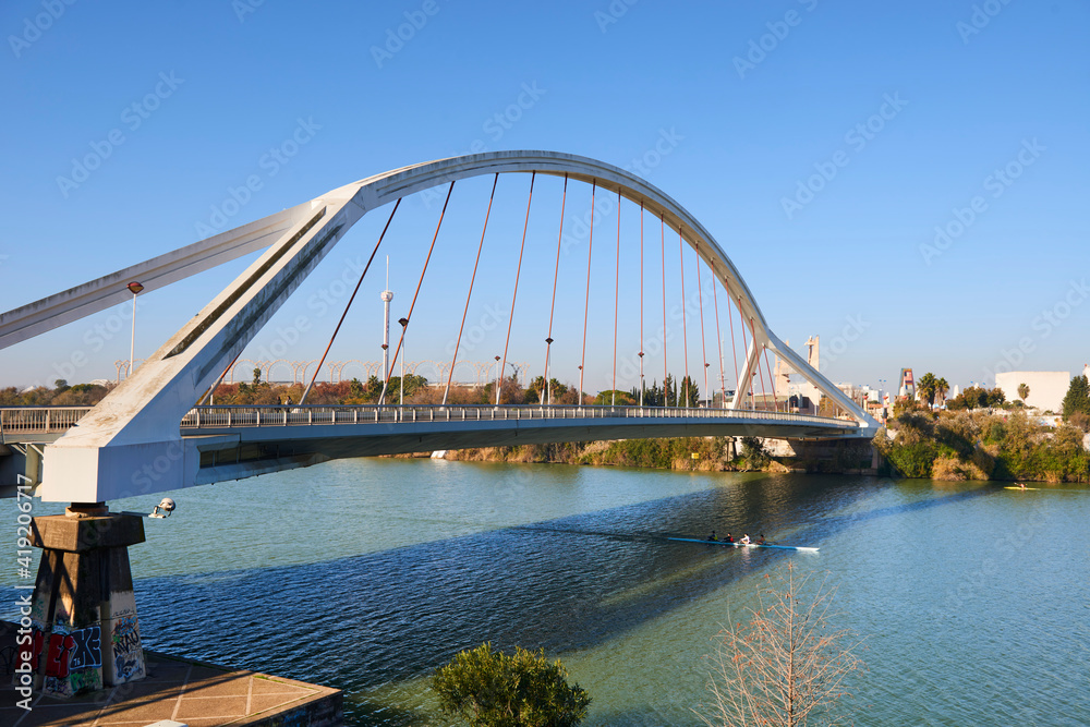 Obraz premium Rowboats in the Guadalquivir river and La Barqueta bridge, Seville, Spain