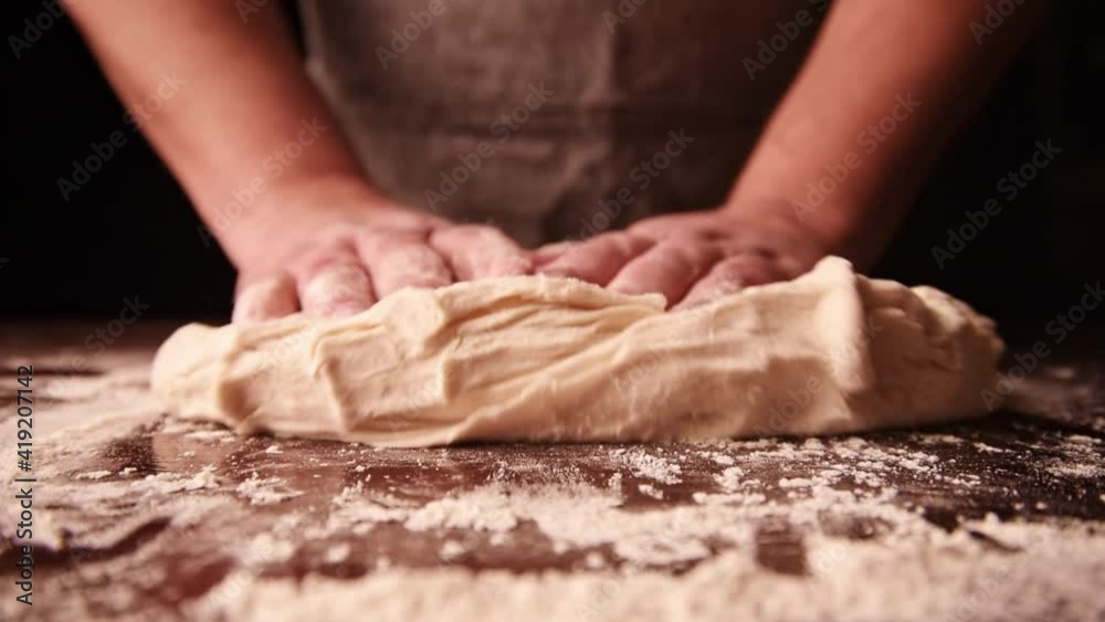 Rolling out dough on a wooden board in kitchen. Process of making pastry Rolling out dough on a wooden board in kitchen. Process of making pastry