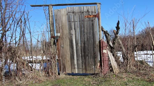 Old broken gate with a damaged structure. Old and abandoned gate in the countryside