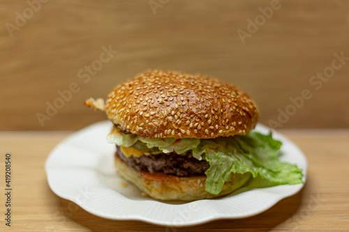 Juicy home made burger on a white plate with a wooden background