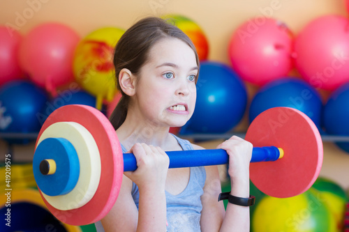 Little girl lifts a barbell in the gym
