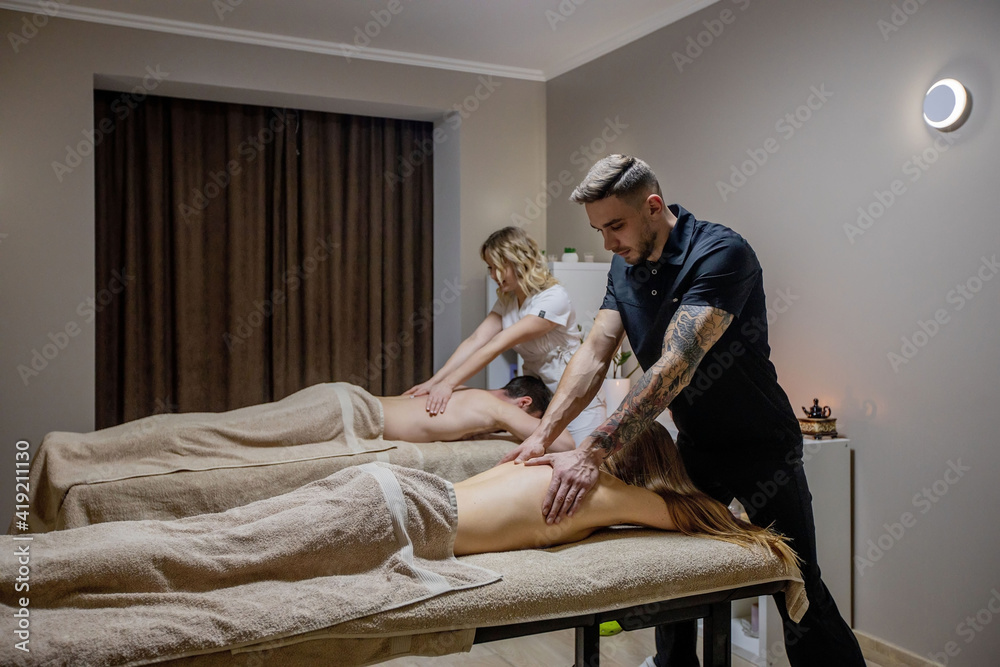 Beautiful couple getting a back massage, weekend spa for couple. Beautiful woman and man relaxes while back massage Beautiful couple getting a back massage, weekend spa for couple. Beautiful woman and man relaxes while back massage
