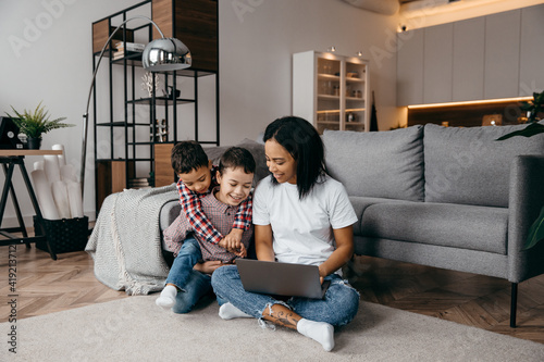 Young afro american mom with two sons make video call by laptop with their daddy. Remote family relationship concept