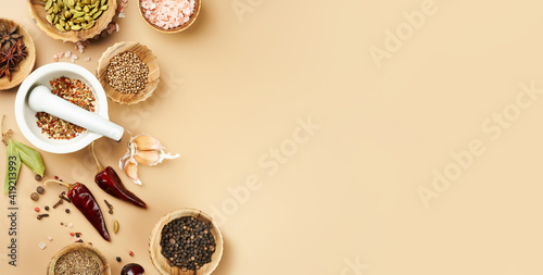 Food mockup with various types of spices Bay leaf, red chili pepper, anise in wooden bowls on a mocca beige color background with copy space. Long food banner with copy space. photo