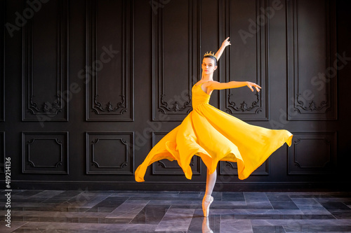 elegant ballerina in pointe shoes dances in long yellow skirt