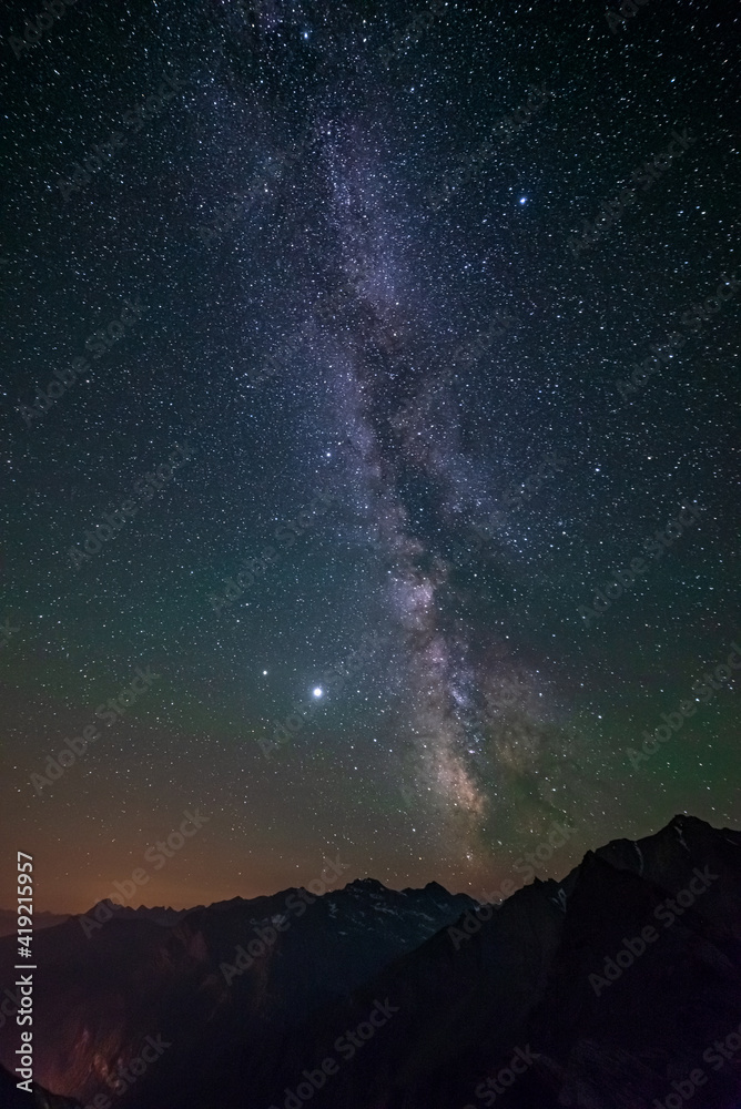 The Milky Way galaxy and the stars in the night sky view from high altitude mountain range, the Alps. Vertical.