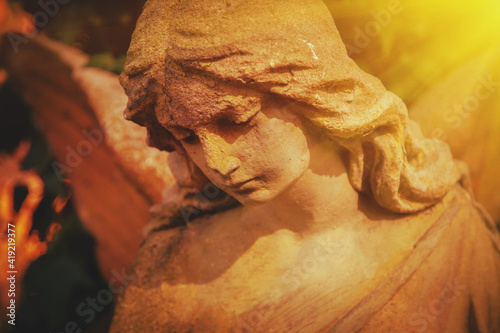 Фотография Antique statue of gold and sad angel in the sunlight