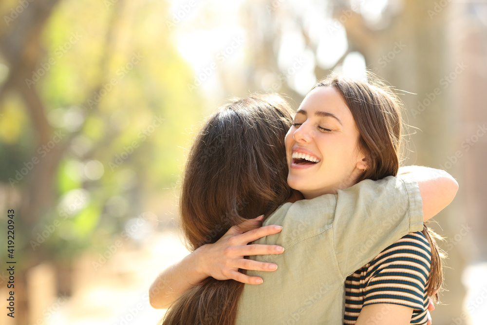 Two happy women embracing meeting in the street