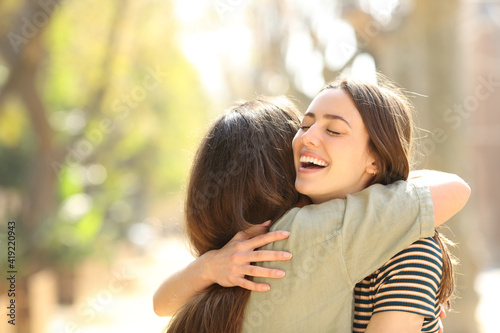 Two happy women embracing meeting in the street