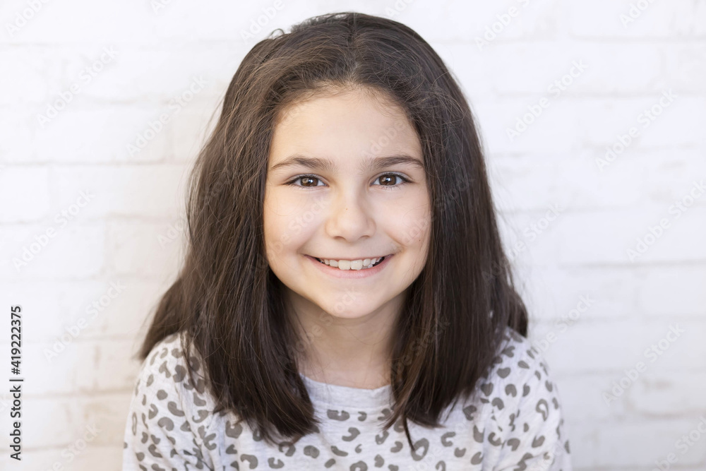 Portrait of a happy smiling latin child girl on white brick wall background Portrait of a happy smiling latin child girl on white brick wall background