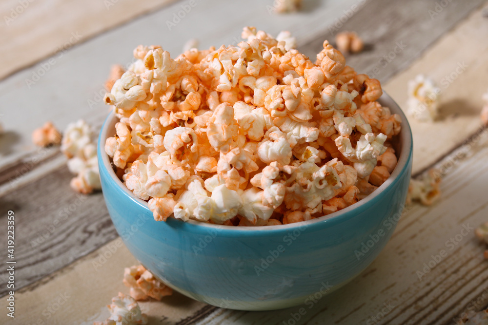 Delicious cheese popcorn in blue bowl in wooden background Delicious cheese popcorn in blue bowl in wooden background
