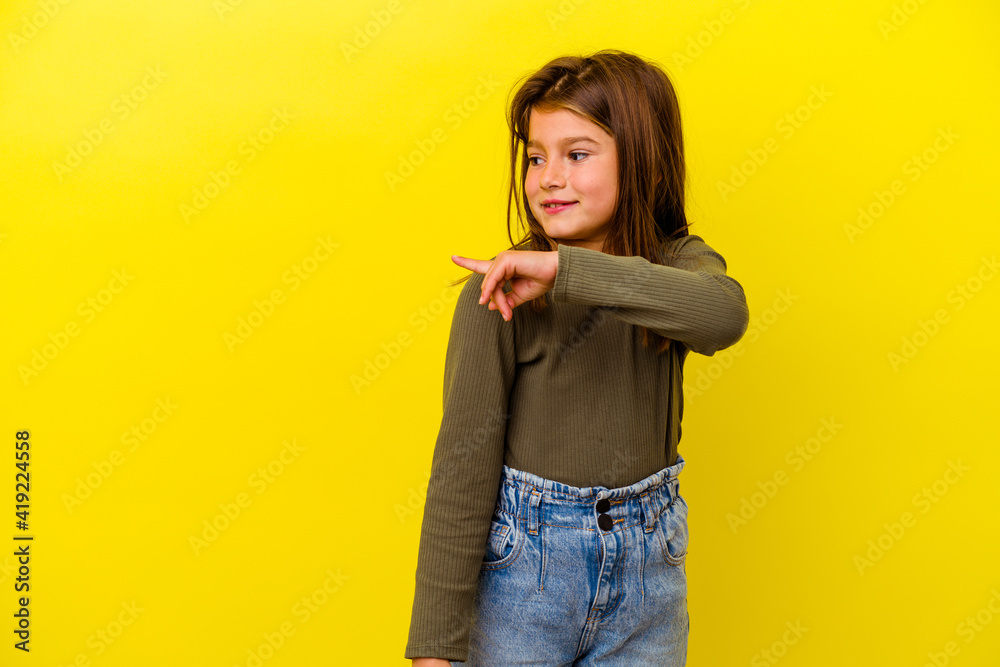 Little caucasian girl isolated on yellow background looks aside smiling, cheerful and pleasant. Little caucasian girl isolated on yellow background looks aside smiling, cheerful and pleasant.