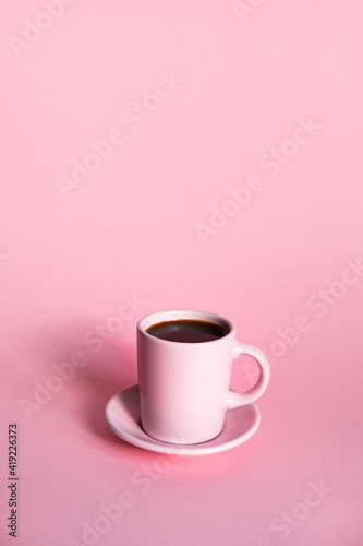 Pink cup of coffee with pink background and coffee beans