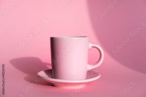 Pink cup of coffee with pink background and coffee beans