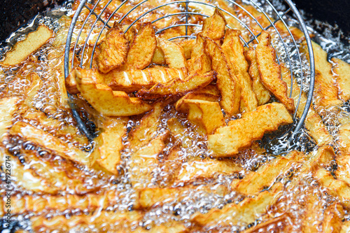 Fototapeta Naklejka Na Ścianę i Meble -  French fries are fried in a deep fat fryer. Checking the dish for readiness. Fast food. French fries are used as a side dish in food.