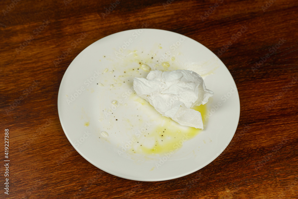 An empty dirty plate with a crumpled napkin An empty dirty plate with a crumpled napkin