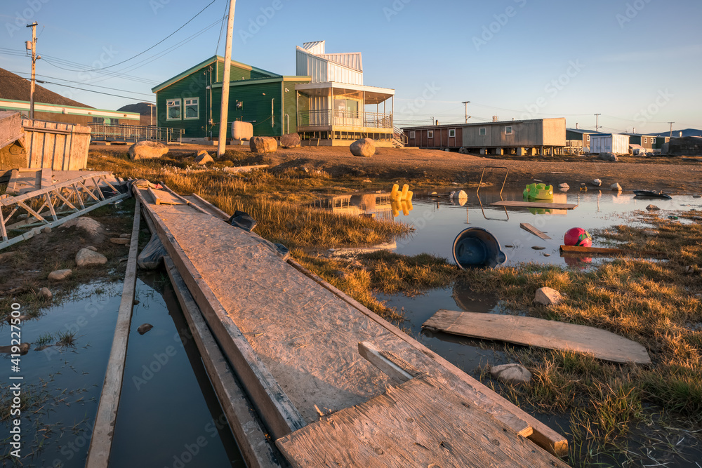Golden hour in Inuit community of Qikiqtarjuaq, Broughton Island, Nunavut, Canada. Parks Canada building reflection on water surface. Settlement in the far north. Arctic community. Golden hour in Inuit community of Qikiqtarjuaq, Broughton Island, Nunavut, Canada. Parks Canada building reflection on water surface. Settlement in the far north. Arctic community.