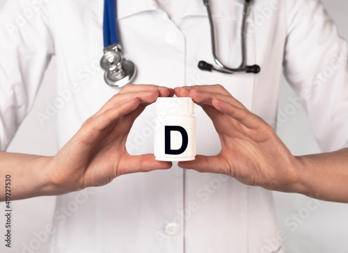 Female doctor or pharmacist in white coat holding jar of D vitamin photo