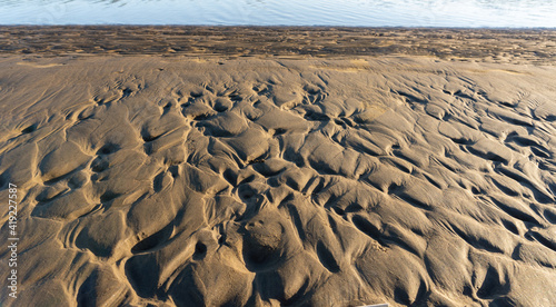 Wavelets formed on the sand and silty-clay shore. Pattern. Brown and gold colors. Sand patterns on the beach at low tide. La Plata River  Atalaya  Buenos Aires. La Plata River.