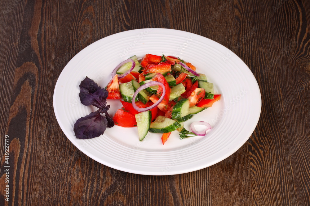 Fresh vegetable salad with onions and basil on a white plate Fresh vegetable salad with onions and basil on a white plate