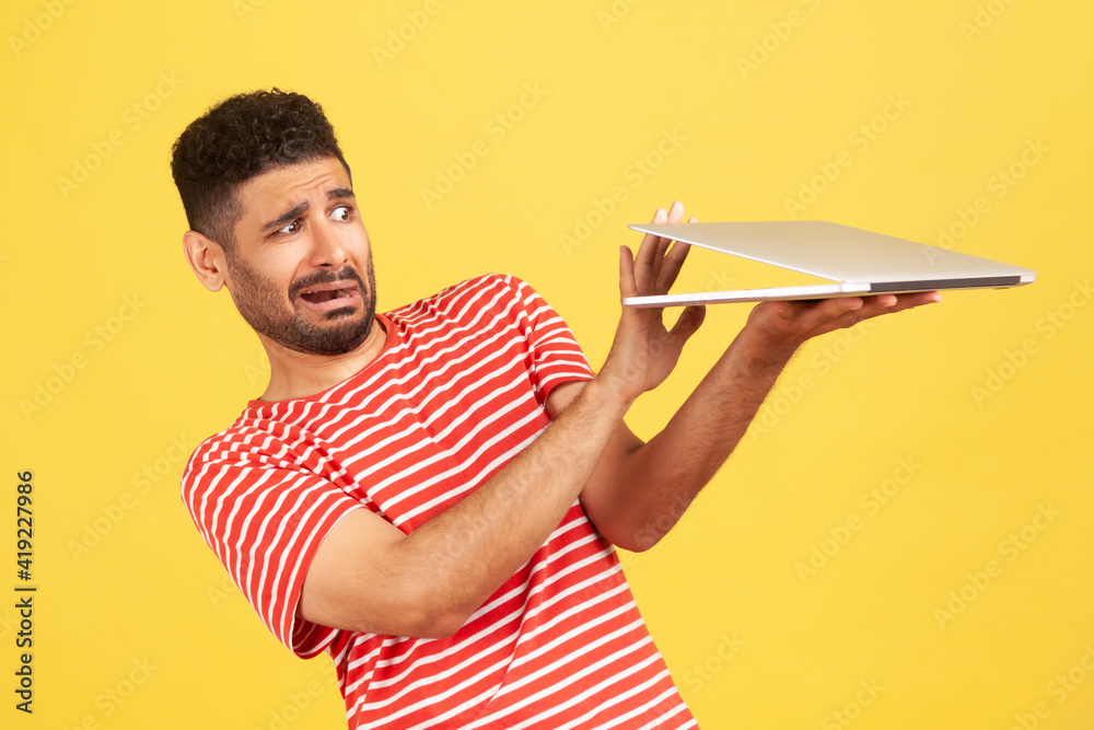 Scared frightened man with beard showing stop to laptop screen with video call, looking terrified, afraid to watch horror or adult content. Indoor studio shot isolated on yellow background Scared frightened man with beard showing stop to laptop screen with video call, looking terrified, afraid to watch horror or adult content. Indoor studio shot isolated on yellow background