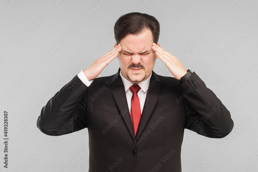 Problems at work, symptoms of disease. Man holding head and have migraine. studio shot. isolated on gray background. handsome businessman with black suit, red tie and mustache. closed eyes. Problems at work, symptoms of disease. Man holding head and have migraine. studio shot. isolated on gray background. handsome businessman with black suit, red tie and mustache. closed eyes.