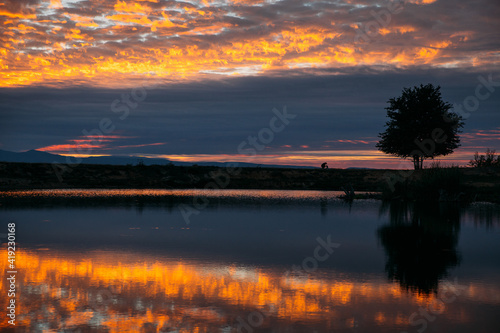 Silhouette of dog and owner running near a lake at sunset.