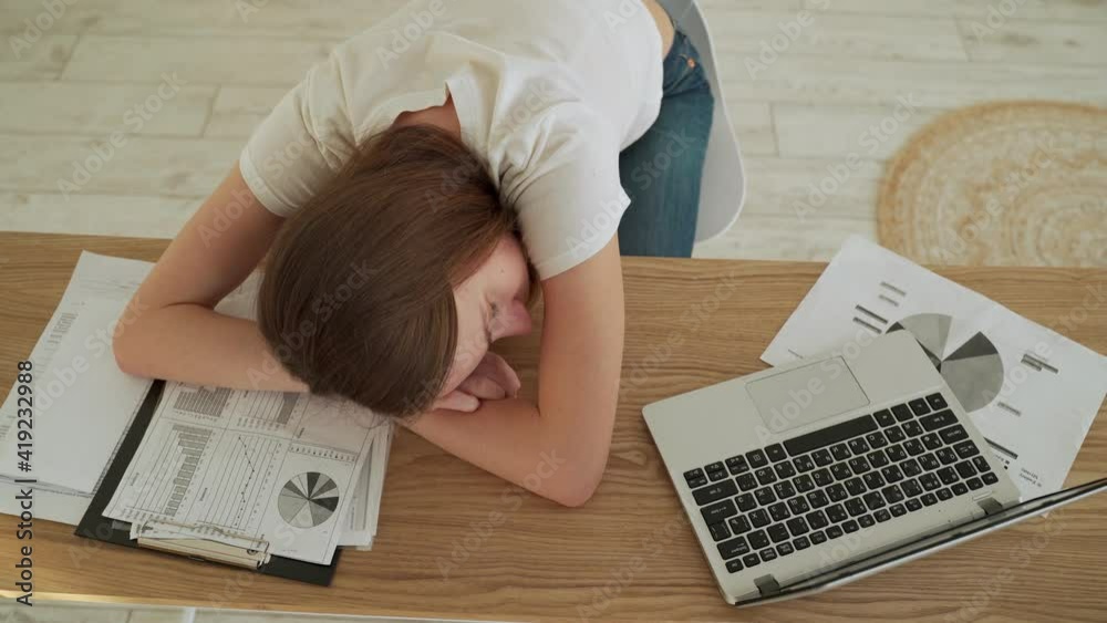 Young tired woman sleeping at her office desk near the laptop Young tired woman sleeping at her office desk near the laptop