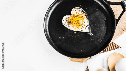 fried eggs in the shape of the heart in a pan. Empty space for text. Flat lay top-down. Light rays fall on the table