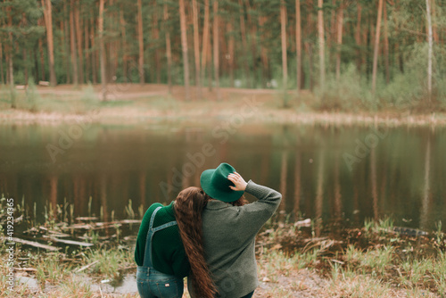 two girlfriends stand on the shore of a forest lake. Female friendship