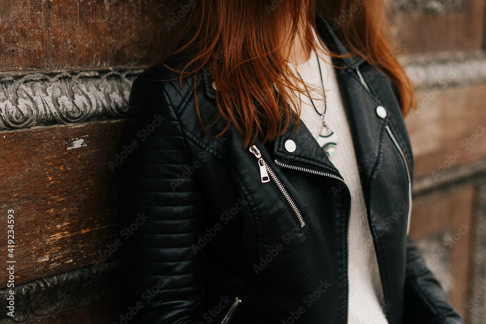 girl in a black leather jacket posing against a wall background - obrazy, fototapety, plakaty 