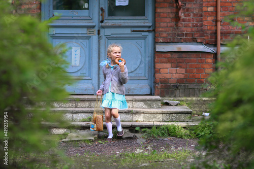 A girl in a blue dress with a string bag of bread, eating a bagel. semitsvetik. Childhood Soviet Union . USSR photo