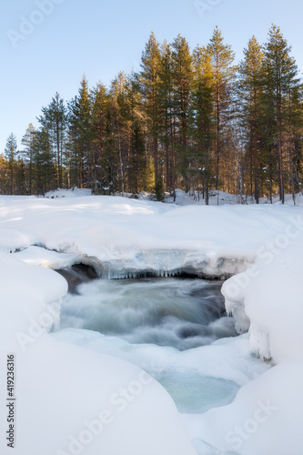 Lapland winter landscape. Lapland rivers are shielded by ice during the winter, only rapids are uncovered due to high speed of water flow.