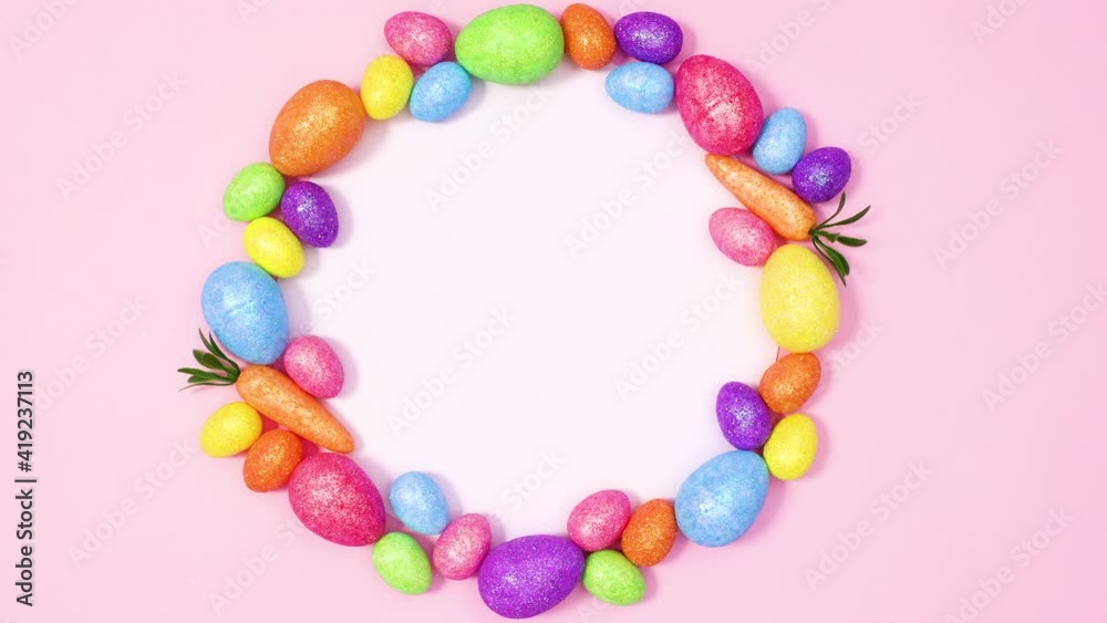 Paper card note surrounded by vibrant Easter eggs on pastel pink background. Stop motion Paper card note surrounded by vibrant Easter eggs on pastel pink background. Stop motion